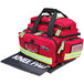 A red Kemp USA professional trauma bag with black straps and a reflective stripe.