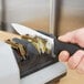 A person using an Edgecraft Chef's Choice professional knife sharpener to sharpen a knife.