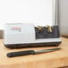 A white and black Edgecraft Chef's Choice 2000 professional knife sharpener on a cutting board with a knife.