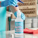 A person in blue gloves pouring Noble Chemical Spiffy Shine into a bottle.