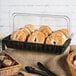 A black rectangular plastic basket filled with bagels and other food items on a counter.