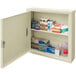 A beige Omnimed wall-mount medical storage cabinet with many boxes and other items inside.