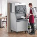 A man in a red apron using a Scotsman air cooled ice machine to fill a glass.