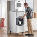 A man standing in front of a Scotsman ice machine pouring water into it.