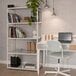 A white desk with a laptop and a white chair next to AR Shelving white shelving unit.