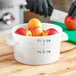 A hand cutting a red apple into a Carlisle food storage container.