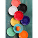 A group of Tuxton Concentrix plates in orange, blue, and white with a black and red spiral pattern.