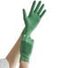 A person wearing Showa green biodegradable nitrile gloves on their hand.