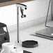 A Regency countertop glass filler on a professional kitchen counter next to a coffee cup.