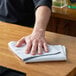 A man cleaning a bar counter with a black and white Choice terry bar towel.