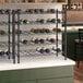 A Regency black epoxy wire wine rack with bottles on it.