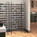 A Regency black wire wine rack filled with bottles of wine.