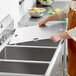 A person in an apron placing a metal lid on a sink.