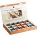A box of Nespresso coffee capsules on a table next to a Nespresso Momento 100 espresso machine.