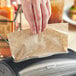 A person holding a brown Tork dispenser napkin.