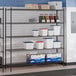 A black epoxy 5-shelf storage rack with various containers and boxes placed on the shelves.