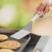 A person using a Dexter-Russell solid turner to flip a pancake.
