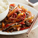 A plate of mixed red and green pepper strips with rice and chopsticks.