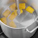 A round chrome steamer rack holding corn on the cob