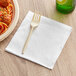 A white 12" x 12" premium luncheon napkin folded into quarters.