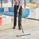 A person using a Lavex white double neoprene foam floor squeegee to clean the floor.