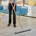 A person using a Lavex Black Neoprene Foam Floor Squeegee to clean a floor.