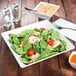 A white bowl with a salad of shrimp and tomatoes in it.