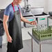 A man wearing a black and red CrewSafe vinyl apron and holding glasses.