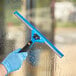 A person in blue gloves using a Lavex squeegee with a black handle to clean a window.