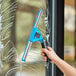 A hand using a Lavex black swivel window cleaning kit to clean a window.