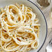 A plate of pasta with Alfredo sauce and a fork.