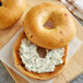 Two Original Bagels with cream cheese and herbs on a cutting board.