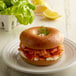 A whole wheat bagel with salmon and cream cheese on it.