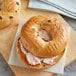 A chocolate chip bagel with cream cheese on top.