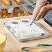 A white silicone baking mold with six round compartments being filled with chocolate batter using a piping bag.