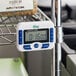 A white Choice Digital 4-channel kitchen timer with clock on a metal rack.