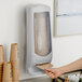 A person using a Tork Xpressnap interfold napkin dispenser on a counter.