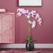 A close-up of a pink and white LCG Sales artificial orchid in a black vase.