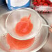 A Tablecraft medium tin single mesh strainer with a red substance being poured through it.