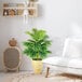 An artificial Areca Palm tree in a wooden basket with handles next to a white chair.