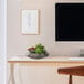 A black bowl with potted artificial succulents on a desk next to a computer monitor.