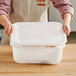 A person holding a white Choice plastic container lid.