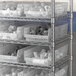 Clear plastic Regency shelf bins on a metal shelving unit.