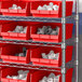 A metal shelving unit with red Regency shelf bins holding white objects.
