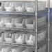 A metal rack with white Regency plastic bins.