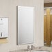 An American Specialties, Inc. Plate Glass Mirror with Stainless Steel Chan-Lok Frame above a sink in a bathroom.