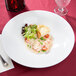 A white CAC porcelain bowl filled with food on a table.