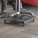 A black Regency multi-purpose dolly under a table with a laptop on it.