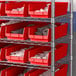 A silver shelf with red Regency shelf bins containing white items.