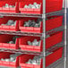 A metal shelving unit with red Regency shelf bins filled with white objects.